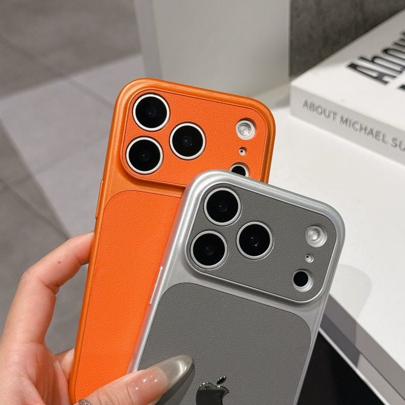 Two phone cases, one orange and one silver, held by a hand with a blurred background.